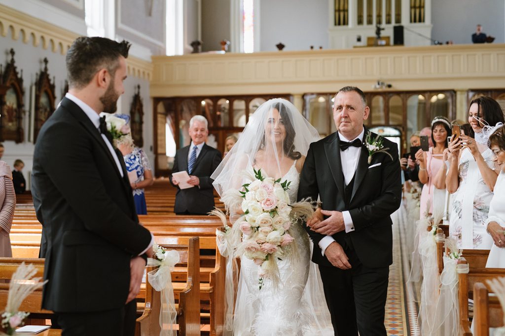 groom looking at bride coming down aisle